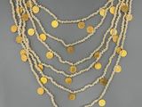 un collier composé de pièces d'or et de perles, présenté sur un mannequin