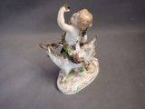 a figurine of a boy sitting on a tree branch
