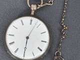 une montre de poche en argent à laquelle est attachée une clé