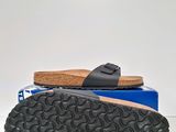 the foot of a pair of black sandals sitting on top of a blue box