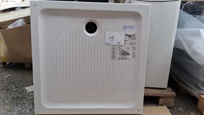 un réfrigérateur blanc posé sur une palette, à côté d'une pile de cartons