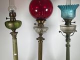 trois vases en verre de couleurs différentes sont alignés sur un fond blanc