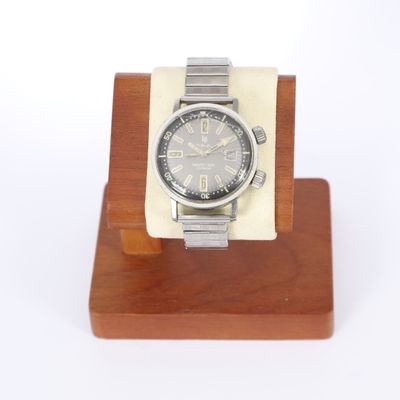 une montre en argent posée sur un socle en bois, sur fond blanc