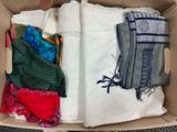 an open cardboard box filled with assorted clothing and scarves