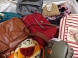 a pile of purses and handbags sitting on a bed