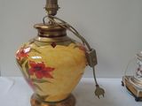 a yellow vase with red flowers on it next to a lamp