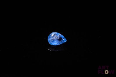 a close up of a blue diamond on a black surface