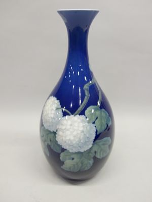 un vase bleu orné de fleurs blanches sur fond blanc