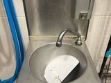 un lavabo dans des toilettes publiques équipé d'un tuyau bleu