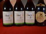 four bottles of wine are lined up on a red table