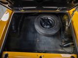 a yellow car with a tire in the trunk of it