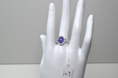 une main sur laquelle est passée une bague sertie d'une pierre bleue
