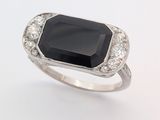 une image représentant une bague en pierre noire et diamant sur fond blanc