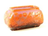 an orange vase with flowers on it on a white surface