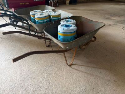 Plusieurs canettes de bière se trouvent dans une brouette, dans un garage.