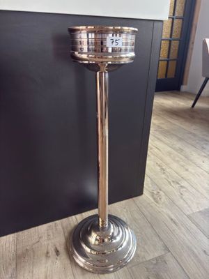 a tall silver candle holder on a wooden floor