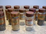 many jars of spices on a counter with a spoon