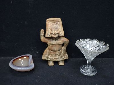 une figurine posée à côté d'un bol en verre et d'une bougie