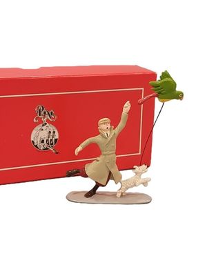 une figurine représentant un homme avec un chien en laisse devant une boîte rouge