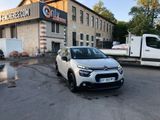 the car is parked in front of a building with a truck parked in front of it