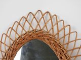 a wicker mirror hanging on a wall next to a black stone