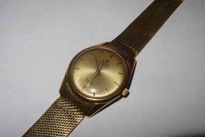 an image of a gold watch sitting on a white surface