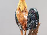 a figurine of a rooster on a clear stand