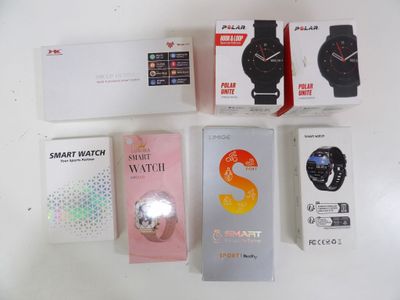 several smart watches are sitting on a white surface next to a box