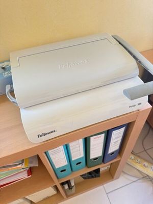 une imprimante posée sur un bureau, à côté d'une bibliothèque