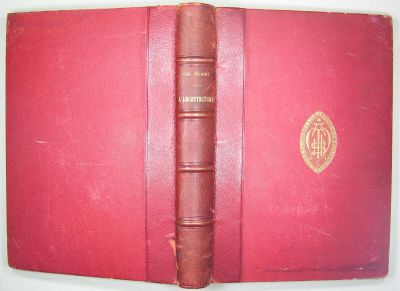 un vieux livre à la couverture rouge posé sur une table blanche