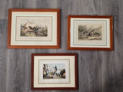 trois reproductions encadrées représentant une scène de chasse sur un mur en bois