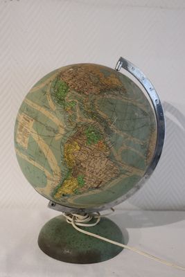 un petit globe posé sur un socle, sur une surface blanche