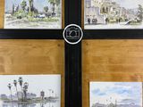 quatre tableaux accrochés au mur d'un immeuble sur lequel se trouve une horloge