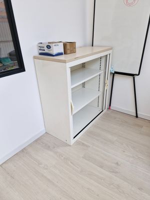 une armoire blanche dans un coin de la pièce, près d'une fenêtre
