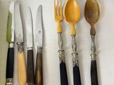 a lot of different types of knives and spoons on the table