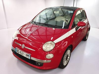 une Fiat rouge avec des bandes blanches, garée dans une pièce blanche