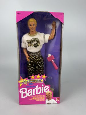 une poupée Barbie aux cheveux blonds, vêtue d'un t-shirt blanc, dans une boîte rose
