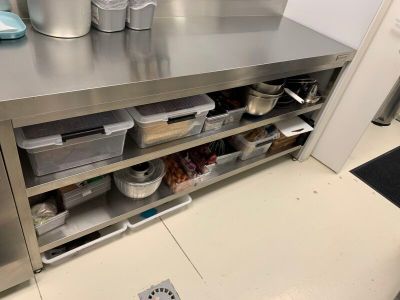 un plan de travail en acier inoxydable dans une cuisine professionnelle, sur lequel sont posées des casseroles et des poêles