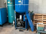 a large blue tank sitting in a garage next to other blue tanks
