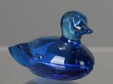 a blue glass duck sitting on top of a table