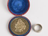 une image représentant une pièce de monnaie dans un étui contenant une bague
