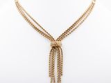 a gold necklace with a chain and a tassel on a mannequin mannequin