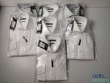six chemises blanches pour homme, dans des sacs en plastique, posées sur une table