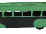 un petit bus jouet vert et noir posé sur une surface blanche