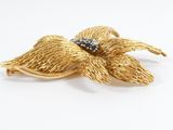 an image of a gold flower brooch with blue stones