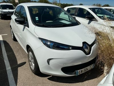 des voitures garées sur un parking, avec des mauvaises herbes qui poussent à l'avant