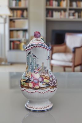 un vase posé sur une table, avec une bibliothèque en arrière-plan