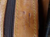 a close up of a brown leather bag with yellow stitching