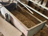 a wooden box filled with hay inside of a barn
