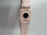 a pink watch with a button on it on a white surface